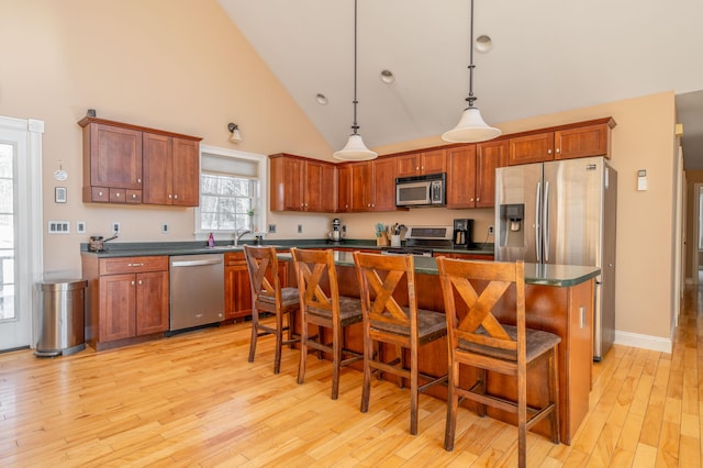 kitchen featuring a kitchen bar, a kitchen island, hanging light fixtures, and appliances with stainless steel finishes