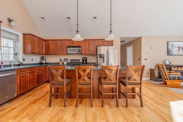 kitchen with pendant lighting, a kitchen bar, stainless steel appliances, light hardwood / wood-style floors, and a kitchen island