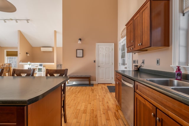 kitchen with a kitchen bar, sink, high vaulted ceiling, light hardwood / wood-style flooring, and stainless steel dishwasher