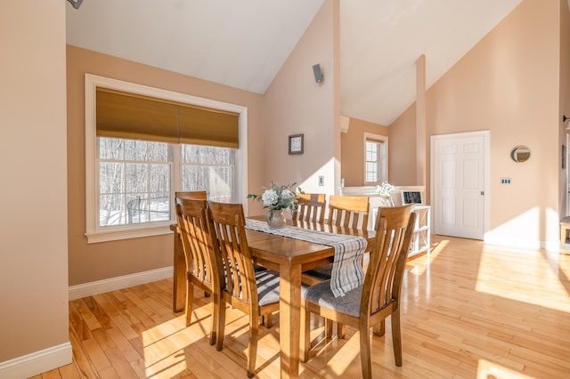 dining space with high vaulted ceiling and light wood-type flooring