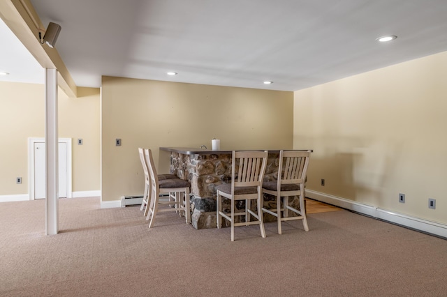 dining space with a baseboard radiator, indoor bar, and light colored carpet