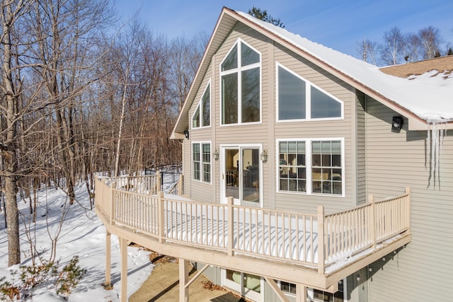 snow covered back of property featuring a wooden deck