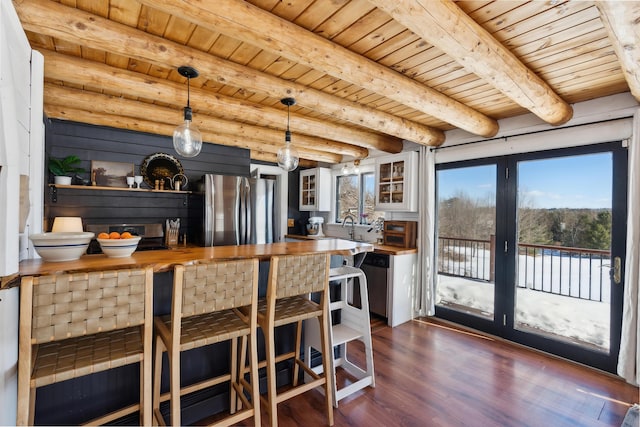 kitchen with butcher block countertops, hanging light fixtures, stainless steel appliances, dark hardwood / wood-style floors, and wooden ceiling