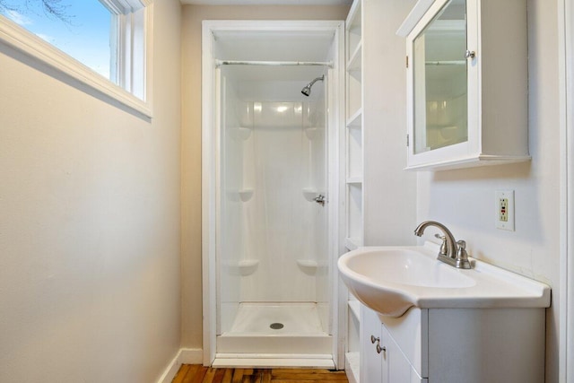 bathroom featuring vanity, wood finished floors, baseboards, and a stall shower