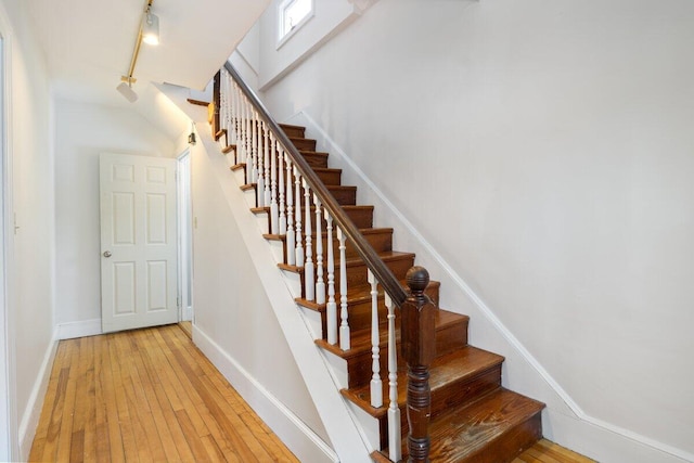 stairway with track lighting, baseboards, and hardwood / wood-style floors