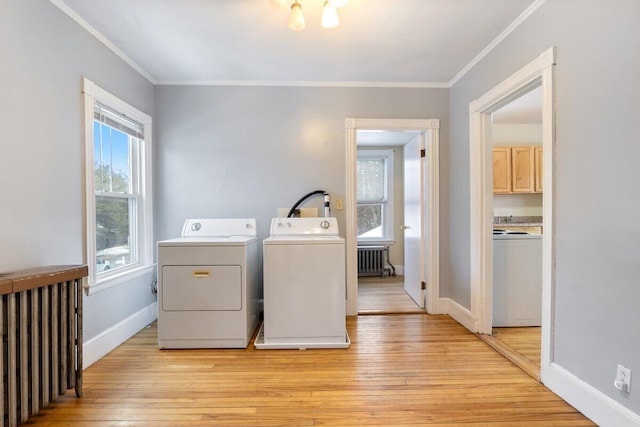 laundry room featuring crown molding, radiator heating unit, washing machine and dryer, and light wood-type flooring