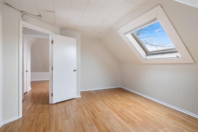 bonus room featuring baseboards, lofted ceiling with skylight, and light wood finished floors