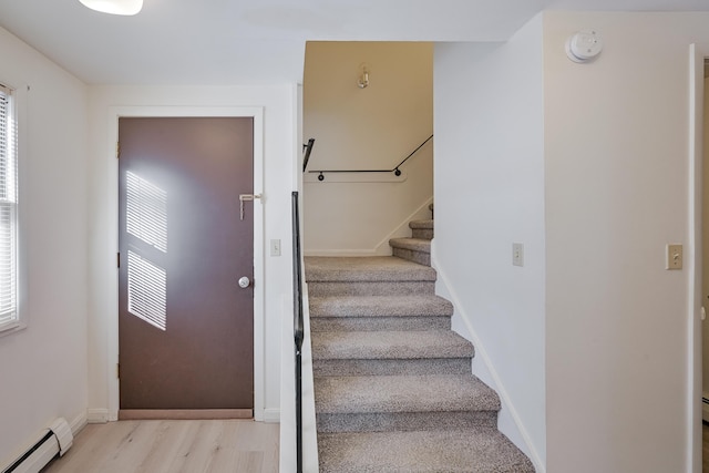 foyer entrance featuring a baseboard heating unit and light hardwood / wood-style floors