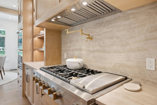 kitchen with tasteful backsplash, stainless steel appliances, light brown cabinetry, and premium range hood