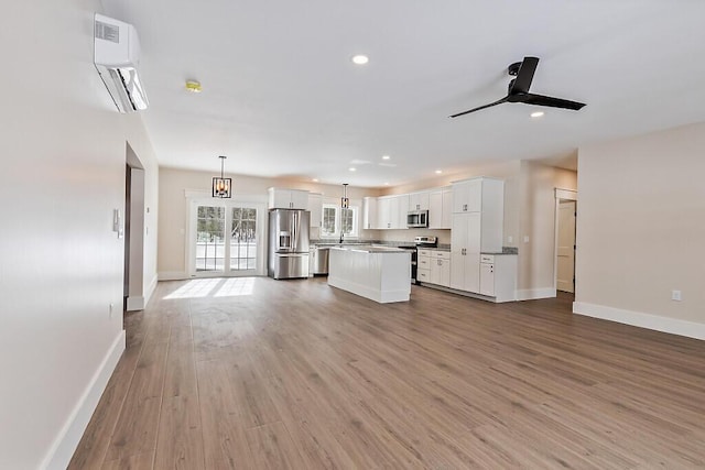 kitchen with a wall mounted AC, decorative light fixtures, stainless steel appliances, and white cabinets