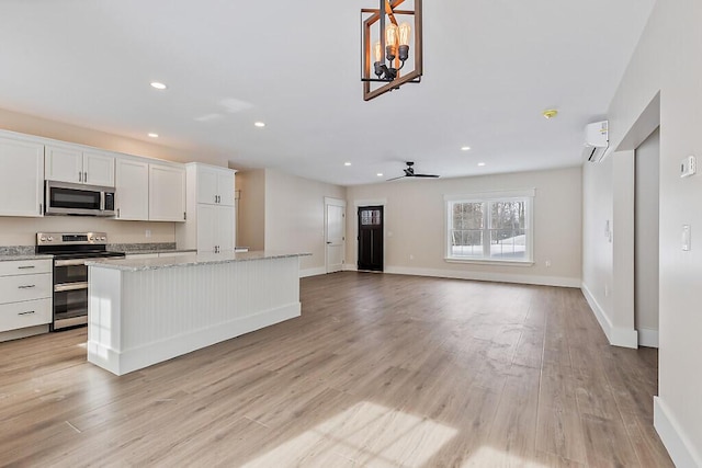 kitchen featuring white cabinetry, stainless steel appliances, a center island, light hardwood / wood-style flooring, and light stone counters