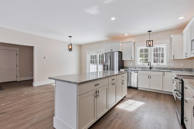 kitchen with white cabinetry, appliances with stainless steel finishes, a kitchen island, and pendant lighting