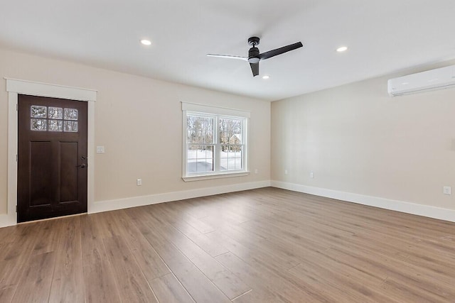 foyer entrance featuring a wall mounted AC, light wood-type flooring, and ceiling fan