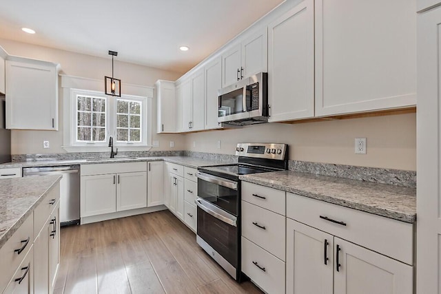 kitchen featuring white cabinets, hanging light fixtures, stainless steel appliances, and sink