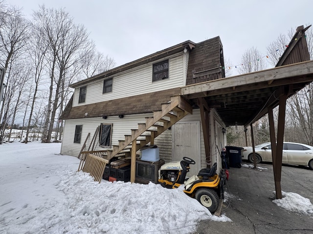 snow covered house featuring stairs