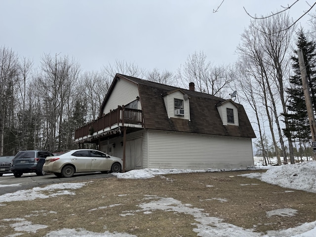 snow covered property with a gambrel roof, a chimney, roof with shingles, a deck, and cooling unit