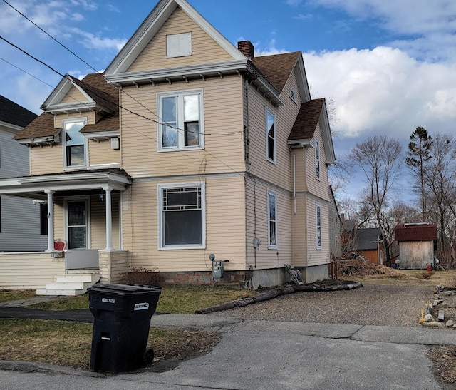 view of front facade featuring covered porch and a chimney