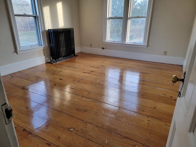 spare room with light wood-type flooring, radiator, and baseboards