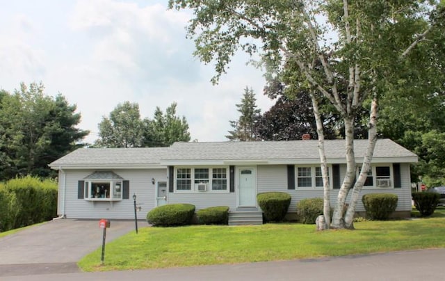 single story home featuring entry steps, aphalt driveway, and a front lawn