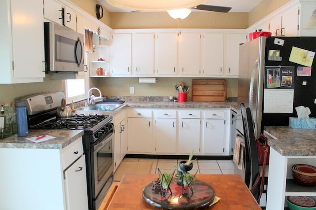 kitchen with light tile patterned floors, stainless steel appliances, open shelves, light countertops, and white cabinets