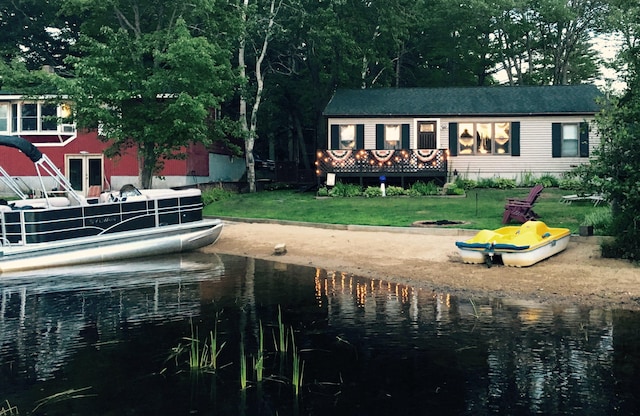 back of property with a water view and a lawn