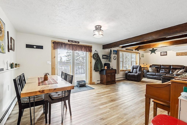 dining area featuring light wood-type flooring, a baseboard heating unit, and a healthy amount of sunlight