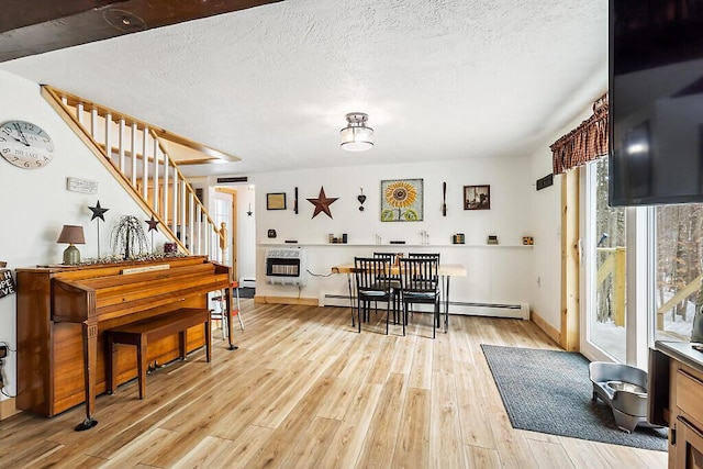 dining room featuring heating unit, light hardwood / wood-style flooring, a baseboard heating unit, and a textured ceiling