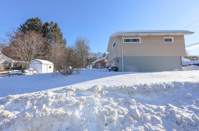 snow covered property featuring a storage shed