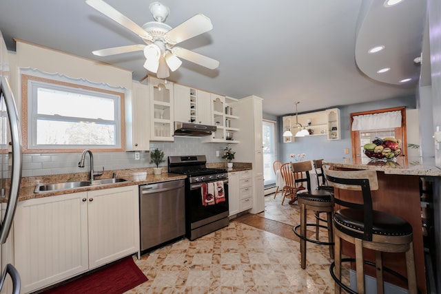 kitchen featuring hanging light fixtures, a breakfast bar area, stainless steel appliances, decorative backsplash, and sink