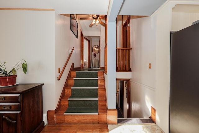 stairway featuring wood-type flooring and ceiling fan