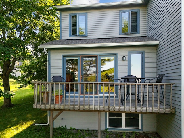 back of house with a wooden deck, a shingled roof, and a yard