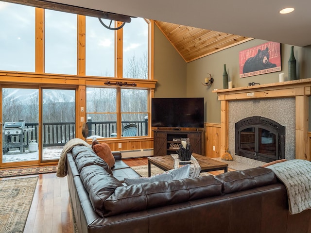 living room with lofted ceiling, wood ceiling, a tile fireplace, a baseboard radiator, and hardwood / wood-style floors