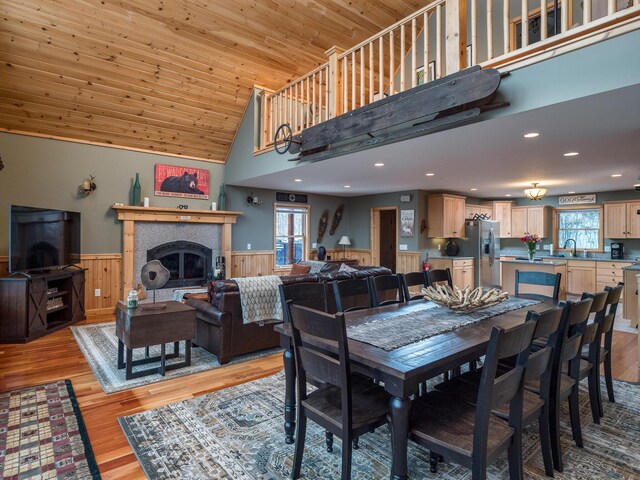 dining space with light hardwood / wood-style floors, a healthy amount of sunlight, wood ceiling, and a fireplace