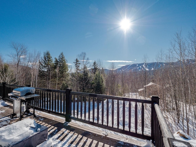 snow covered deck featuring a mountain view and area for grilling