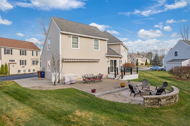 rear view of property featuring a yard, a residential view, a patio, and a fire pit