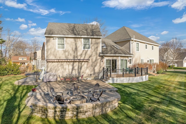 rear view of property featuring an outdoor fire pit, a shingled roof, a lawn, a patio, and a deck