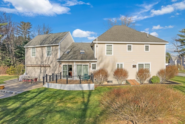 rear view of property with a shingled roof, a patio area, a lawn, and a wooden deck