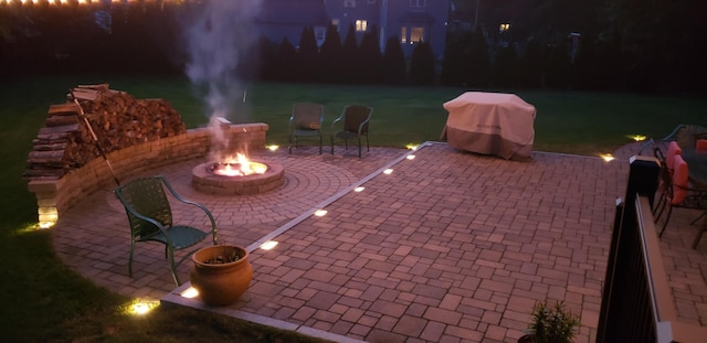 patio at night with an outdoor fire pit and a grill