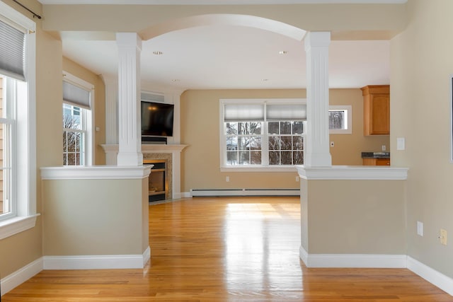 kitchen with a baseboard heating unit, a fireplace, decorative columns, and light wood-style flooring