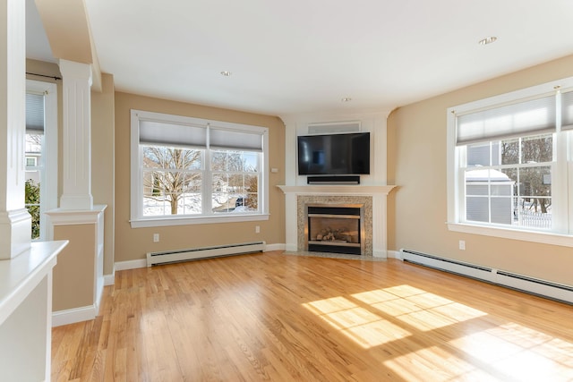 unfurnished living room featuring a healthy amount of sunlight, light wood-style floors, a baseboard radiator, and a fireplace with flush hearth