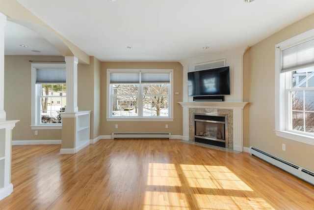 unfurnished living room with light wood-type flooring, decorative columns, a baseboard heating unit, and baseboard heating