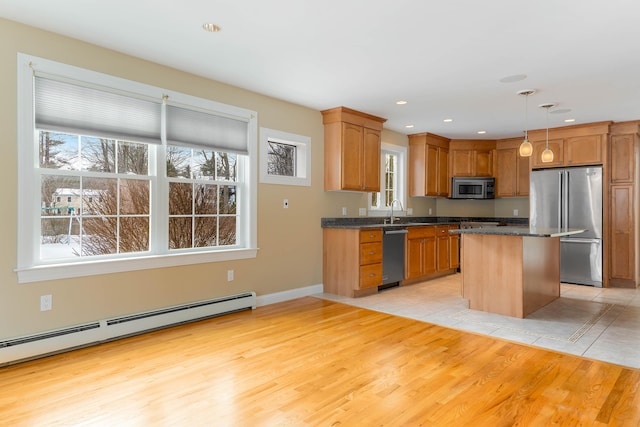 kitchen featuring a center island, pendant lighting, baseboard heating, appliances with stainless steel finishes, and light wood-style floors