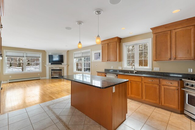 kitchen with light tile patterned floors, appliances with stainless steel finishes, open floor plan, a baseboard heating unit, and pendant lighting