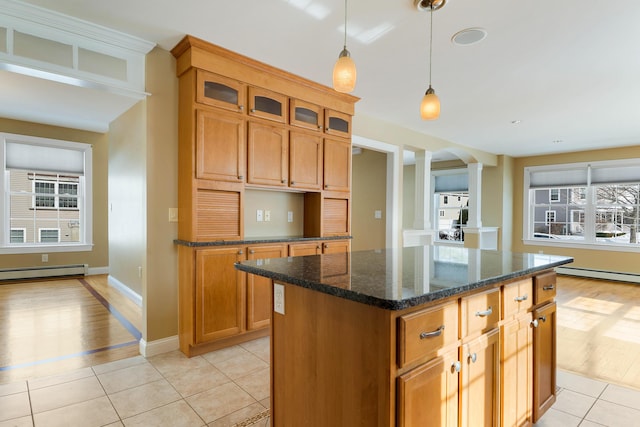 kitchen with a center island, light tile patterned floors, baseboard heating, glass insert cabinets, and dark stone counters