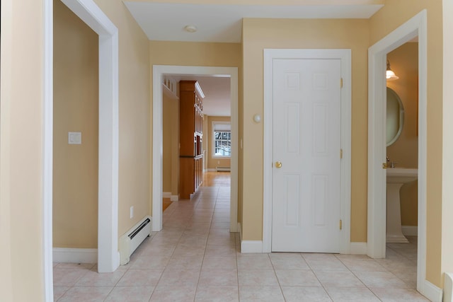 hallway featuring light tile patterned floors, a baseboard radiator, baseboards, and baseboard heating