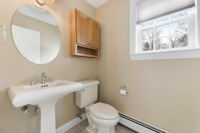 bathroom featuring tile patterned flooring, toilet, a baseboard heating unit, a sink, and baseboards