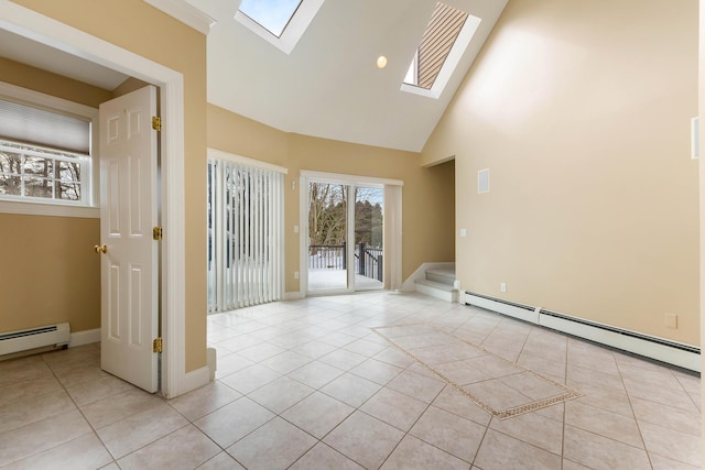 spare room featuring a skylight, light tile patterned floors, baseboards, baseboard heating, and high vaulted ceiling