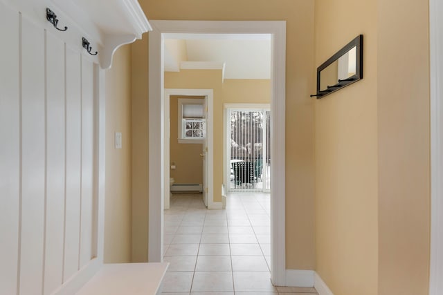 hallway with a baseboard radiator, baseboards, and light tile patterned flooring