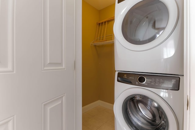 laundry room featuring stacked washer and dryer, laundry area, baseboards, and tile patterned floors