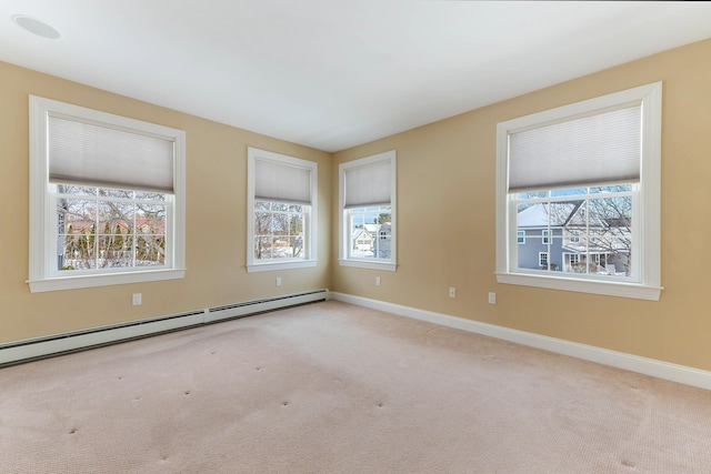 spare room with a healthy amount of sunlight, baseboards, baseboard heating, and light colored carpet